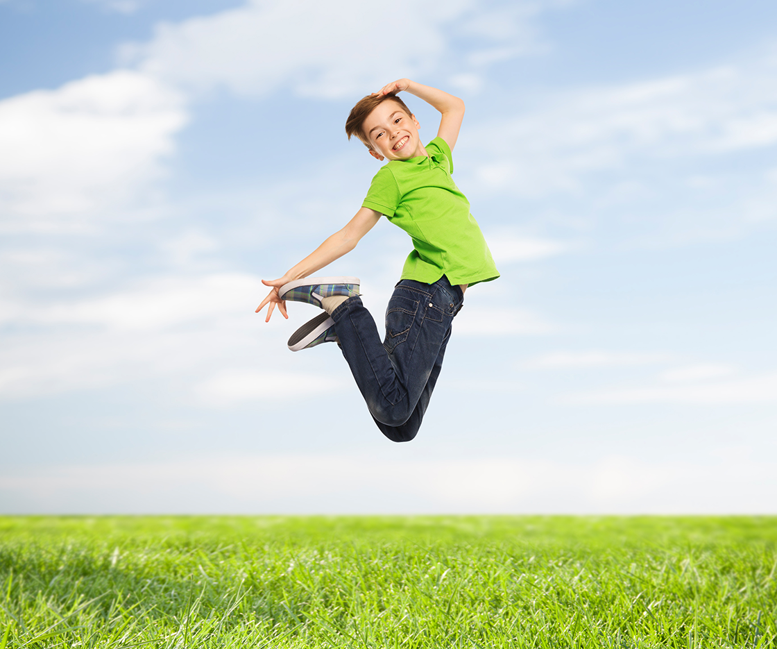 happiness-childhood-freedom-movement-and-people-concept-smiling-boy-jumping-in-air-over-blue-sky-and-grass-background